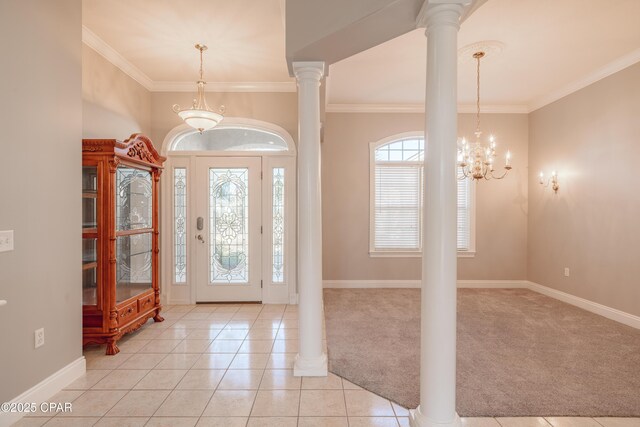 carpeted foyer with a notable chandelier, crown molding, and decorative columns