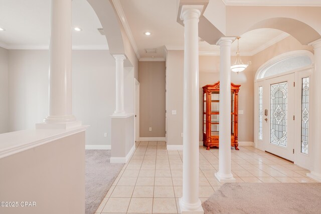 foyer entrance with light colored carpet, ornamental molding, a chandelier, and decorative columns