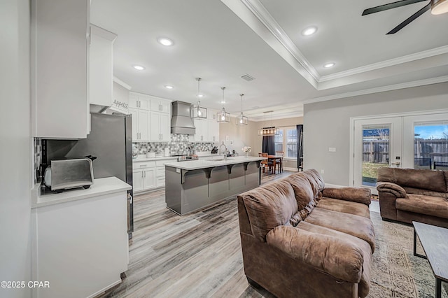 living room with french doors, light hardwood / wood-style floors, sink, ornamental molding, and ceiling fan