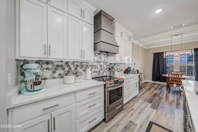 kitchen with pendant lighting, white cabinets, stainless steel range with electric stovetop, and custom exhaust hood