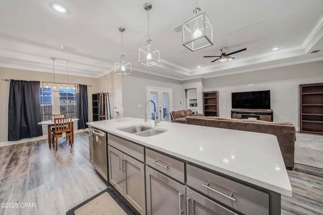 kitchen with decorative light fixtures, sink, dishwasher, and an island with sink