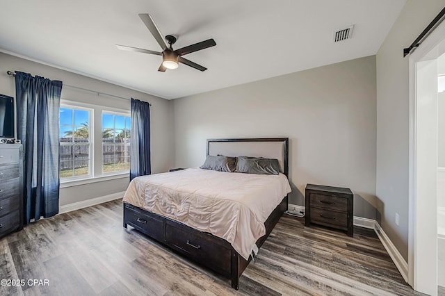 bedroom with ceiling fan, a barn door, and hardwood / wood-style flooring