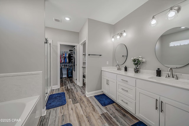 bathroom with vanity, wood-type flooring, and a bath