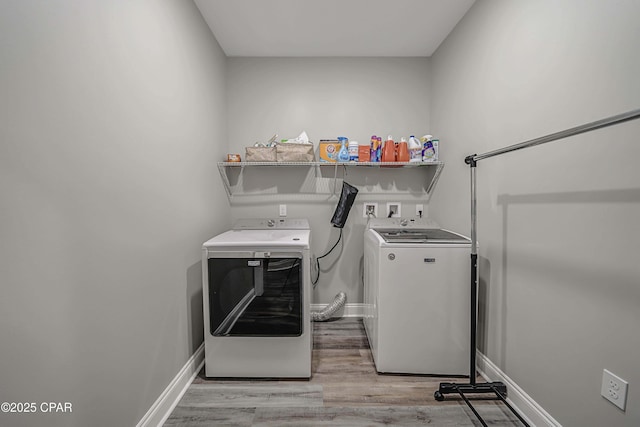 clothes washing area with separate washer and dryer and light hardwood / wood-style floors