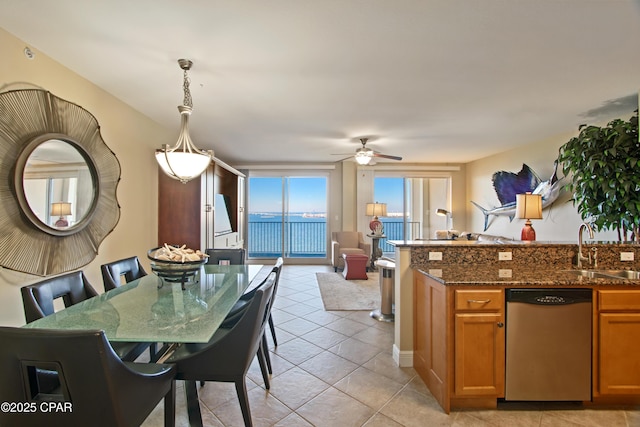 kitchen featuring ceiling fan, sink, dark stone countertops, dishwasher, and hanging light fixtures