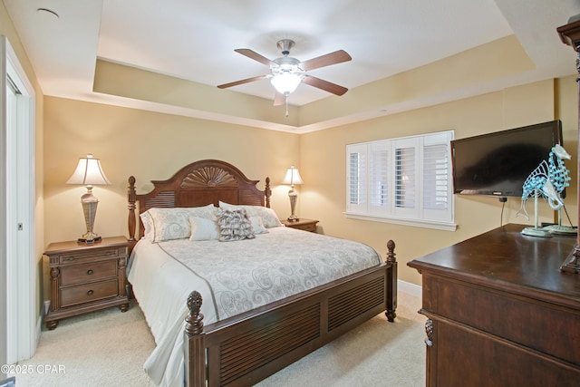 carpeted bedroom with a raised ceiling and ceiling fan