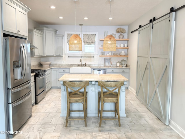 kitchen with a breakfast bar, decorative light fixtures, a center island, stainless steel appliances, and a barn door