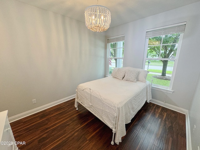 bedroom featuring an inviting chandelier and dark hardwood / wood-style flooring