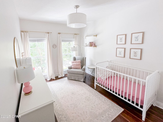 bedroom featuring a nursery area and dark hardwood / wood-style flooring