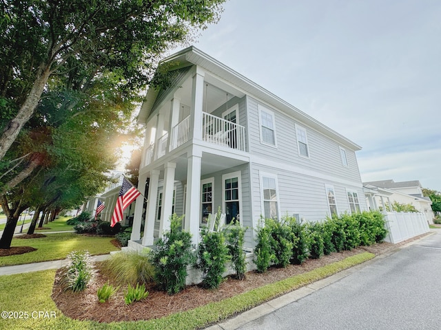 view of side of home with a yard and a balcony