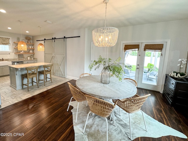 dining space with a healthy amount of sunlight, wood-type flooring, a barn door, and sink