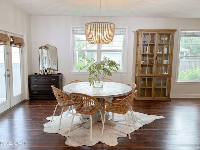 dining area with dark hardwood / wood-style floors, an inviting chandelier, and french doors