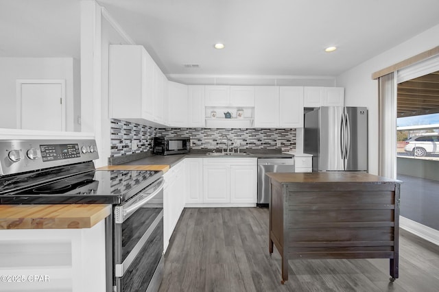 kitchen with butcher block countertops, white cabinetry, sink, and appliances with stainless steel finishes