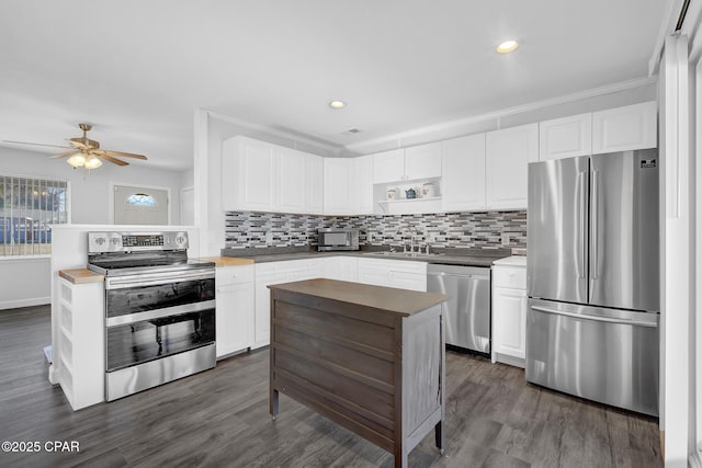 kitchen with white cabinetry, ceiling fan, stainless steel appliances, dark hardwood / wood-style floors, and decorative backsplash