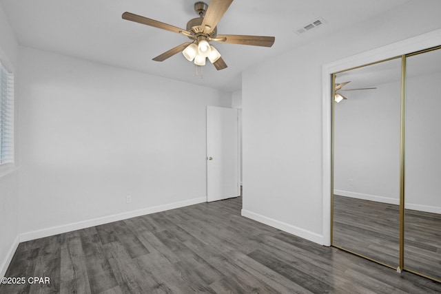 unfurnished bedroom with ceiling fan, dark hardwood / wood-style floors, and a closet