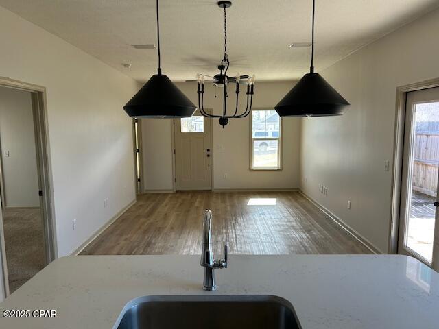 kitchen with sink, pendant lighting, plenty of natural light, and wood-type flooring