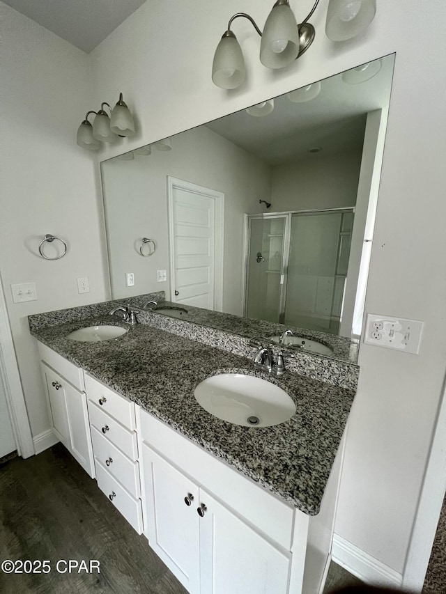 bathroom with wood-type flooring, a shower with door, and vanity