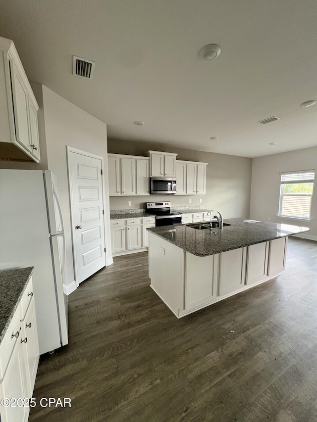 kitchen featuring a center island with sink, white cabinets, dark stone countertops, and stainless steel appliances