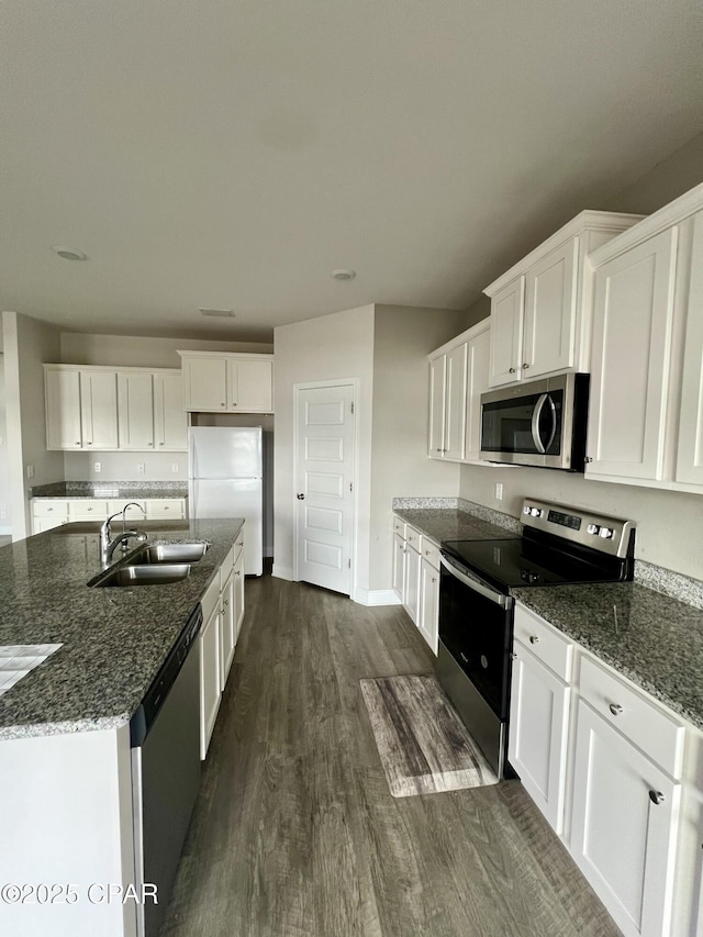 kitchen with a center island with sink, white cabinets, dark hardwood / wood-style floors, and appliances with stainless steel finishes