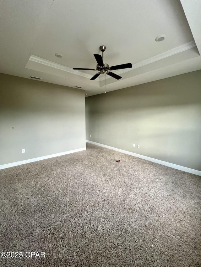 carpeted empty room with ceiling fan and a tray ceiling