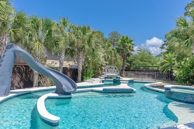 view of swimming pool featuring an in ground hot tub and a water slide