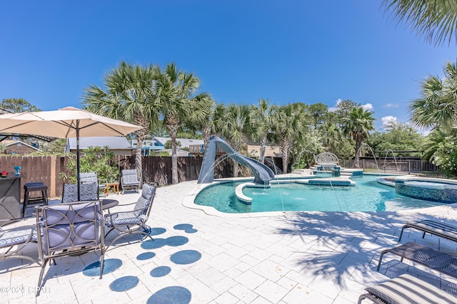 view of pool featuring an in ground hot tub, a water slide, pool water feature, and a patio area