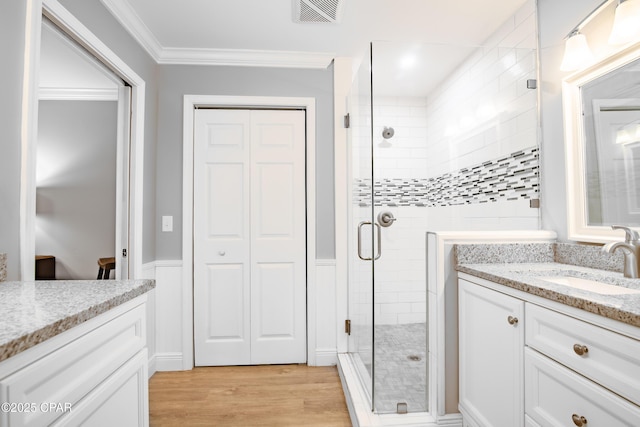 bathroom featuring hardwood / wood-style floors, vanity, crown molding, and walk in shower