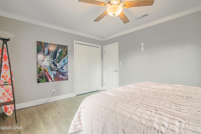 bedroom featuring ceiling fan, light wood-type flooring, crown molding, and a closet