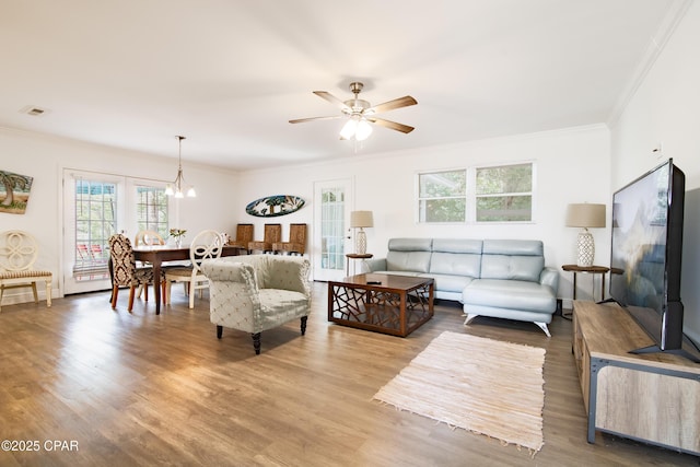 living room with crown molding, ceiling fan with notable chandelier, and hardwood / wood-style flooring