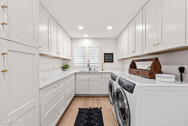 laundry room featuring independent washer and dryer, sink, cabinets, and light wood-type flooring