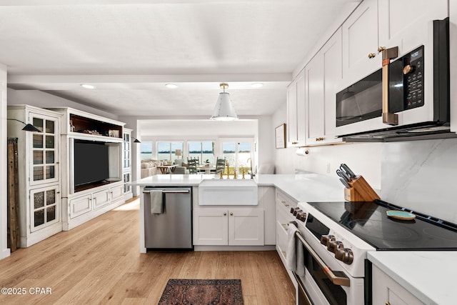 kitchen with pendant lighting, sink, light hardwood / wood-style floors, white cabinetry, and stainless steel appliances