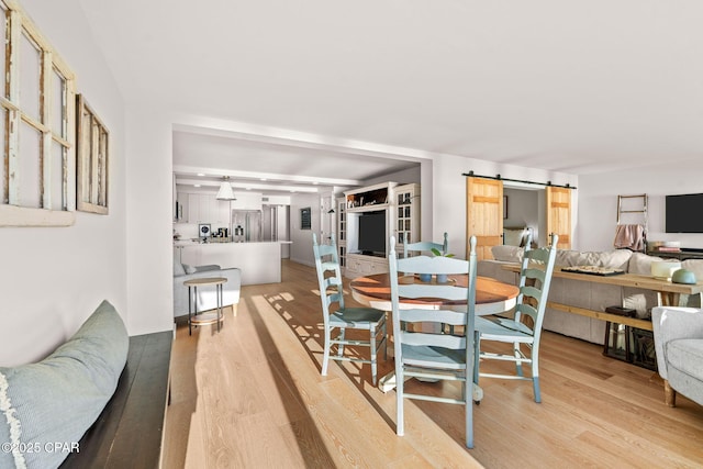 dining area featuring a barn door and light wood-type flooring