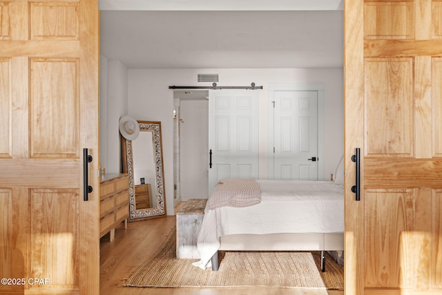 bedroom with a barn door and hardwood / wood-style floors