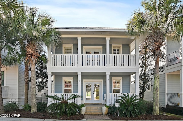 raised beach house featuring a balcony and french doors