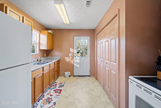 kitchen featuring sink, white fridge, and a textured ceiling