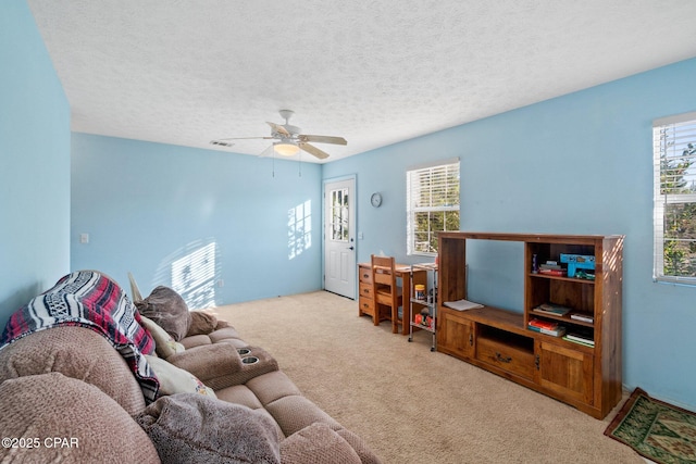 carpeted living room with ceiling fan and a textured ceiling