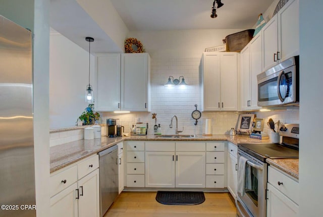 kitchen featuring decorative light fixtures, decorative backsplash, sink, appliances with stainless steel finishes, and white cabinets