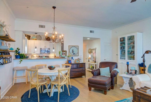 dining room with crown molding, light hardwood / wood-style floors, and a notable chandelier