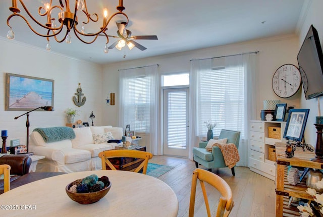 living room with ceiling fan with notable chandelier, a wealth of natural light, light hardwood / wood-style floors, and ornamental molding