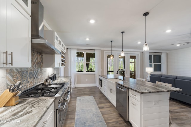 6509 W Sundew Marsh Trl, Panama City Beach, FL 32413 - kitchen featuring stainless steel appliances, wall chimney range hood, a sink, a kitchen island with sink, and light stone countertops