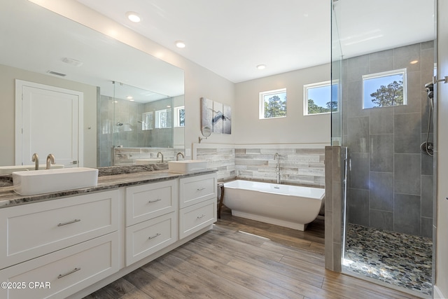 6509 W Sundew Marsh Trl, Panama City Beach, FL 32413 - bathroom featuring a stall shower, double vanity, a freestanding tub, wood finished floors, and tile walls