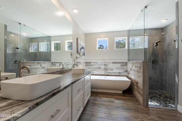 6509 W Sundew Marsh Trl, Panama City Beach, FL 32413 - bathroom featuring healthy amount of natural light, tile walls, a tile shower, wood finished floors, and double vanity