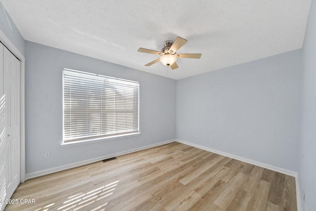 empty room with ceiling fan and light hardwood / wood-style floors