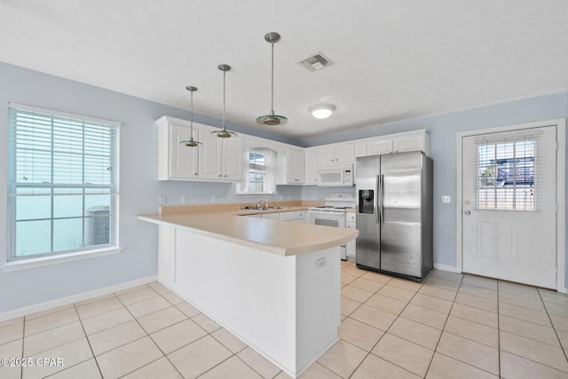 kitchen featuring white appliances, white cabinets, sink, decorative light fixtures, and kitchen peninsula