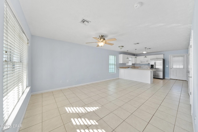 unfurnished living room featuring light tile patterned floors and ceiling fan