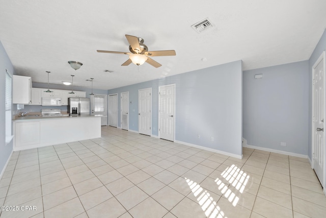 unfurnished living room featuring light tile patterned floors, ceiling fan, and sink