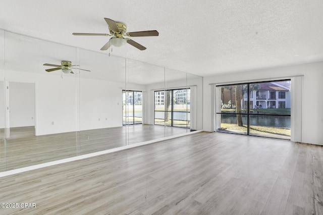 empty room with ceiling fan, light hardwood / wood-style floors, and a textured ceiling