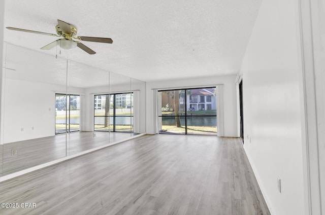 empty room featuring a textured ceiling, ceiling fan, and light hardwood / wood-style flooring