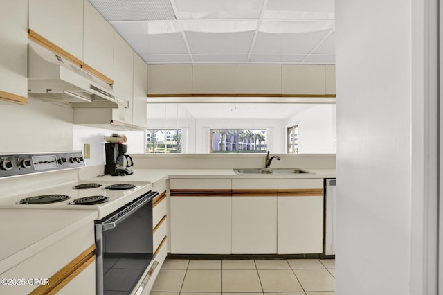 kitchen featuring a paneled ceiling, white electric range oven, light tile patterned floors, white cabinets, and sink