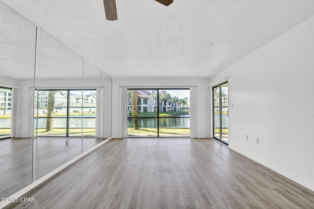 empty room featuring ceiling fan, a water view, and a wealth of natural light